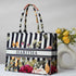 Floral and striped tote bag with 'HARITHA' branding next to a vase with flowers on a light background