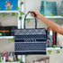 Navy blue tote bag with white patterns and 'DIVYA' branding held by a person in a store setting.
